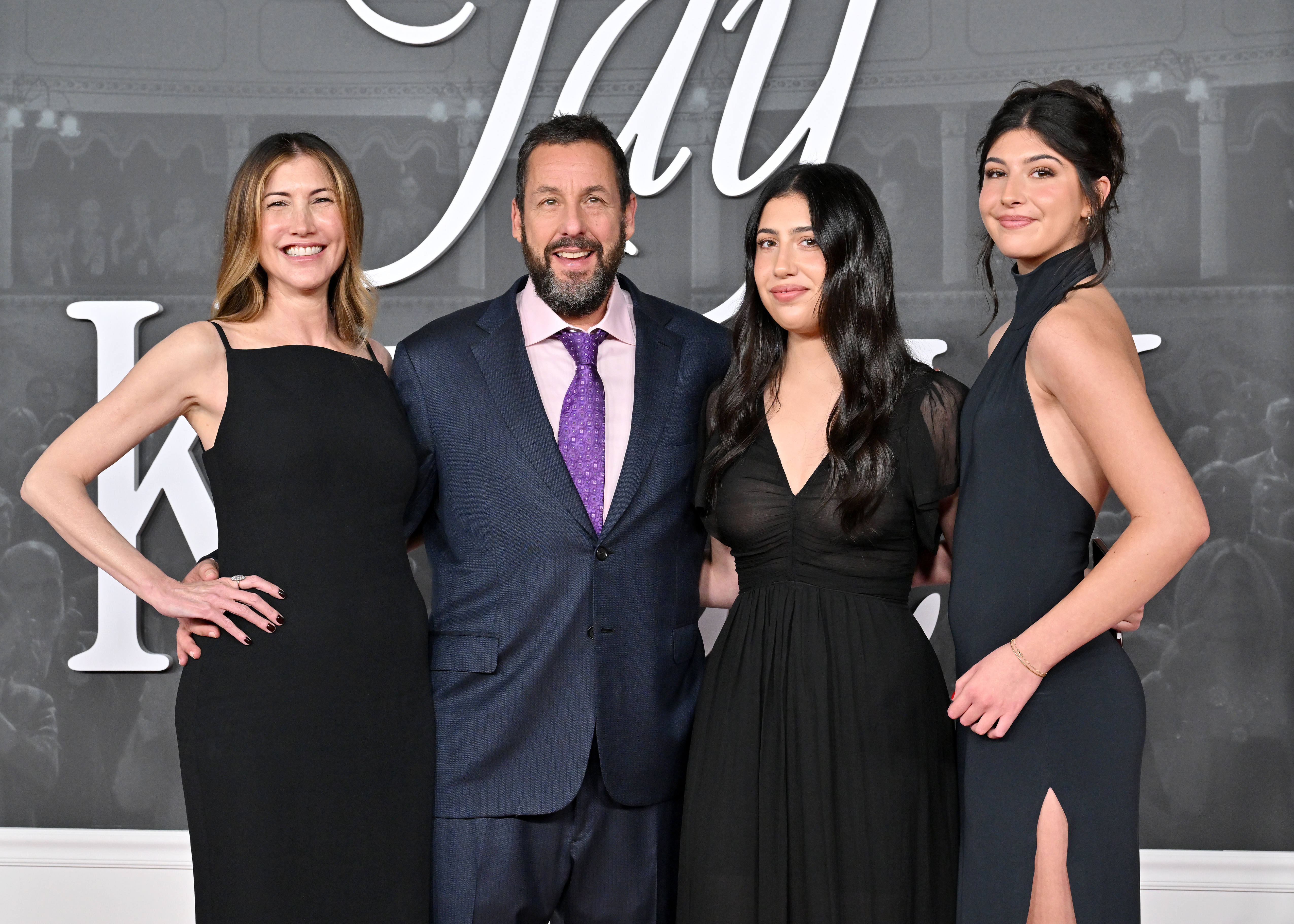 Jackie beams the widest smile as she, her husband Adam, and their daughters Sadie and Sunny Sandler wrap their arms around each other’s waists, pulling close for a heartwarming family photo at the "Jay Kelly" premiere.