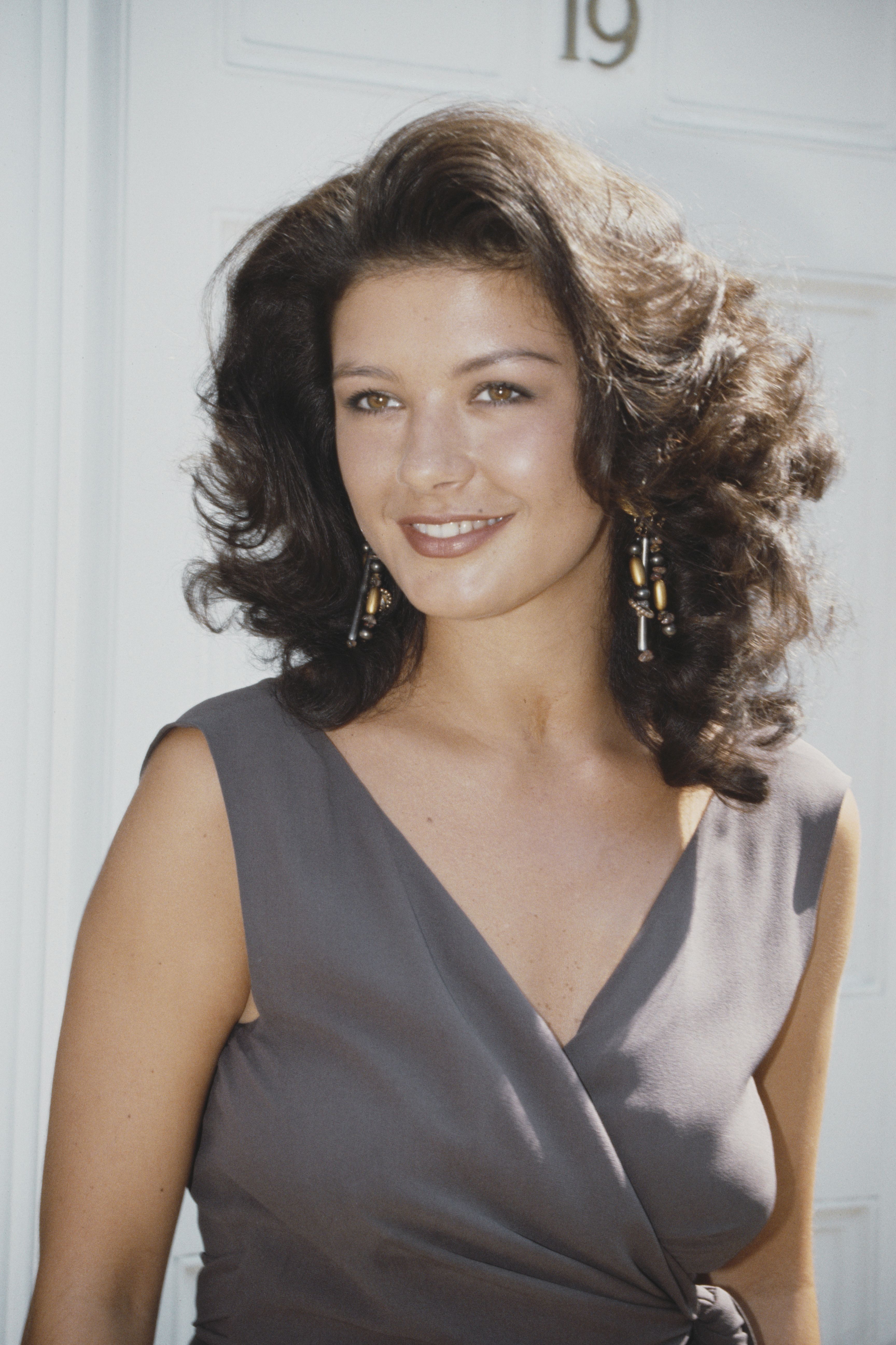 Zeta-Jones looking effortlessly beautiful with blown-out curls and a gray wrap-around top circa 1991.
