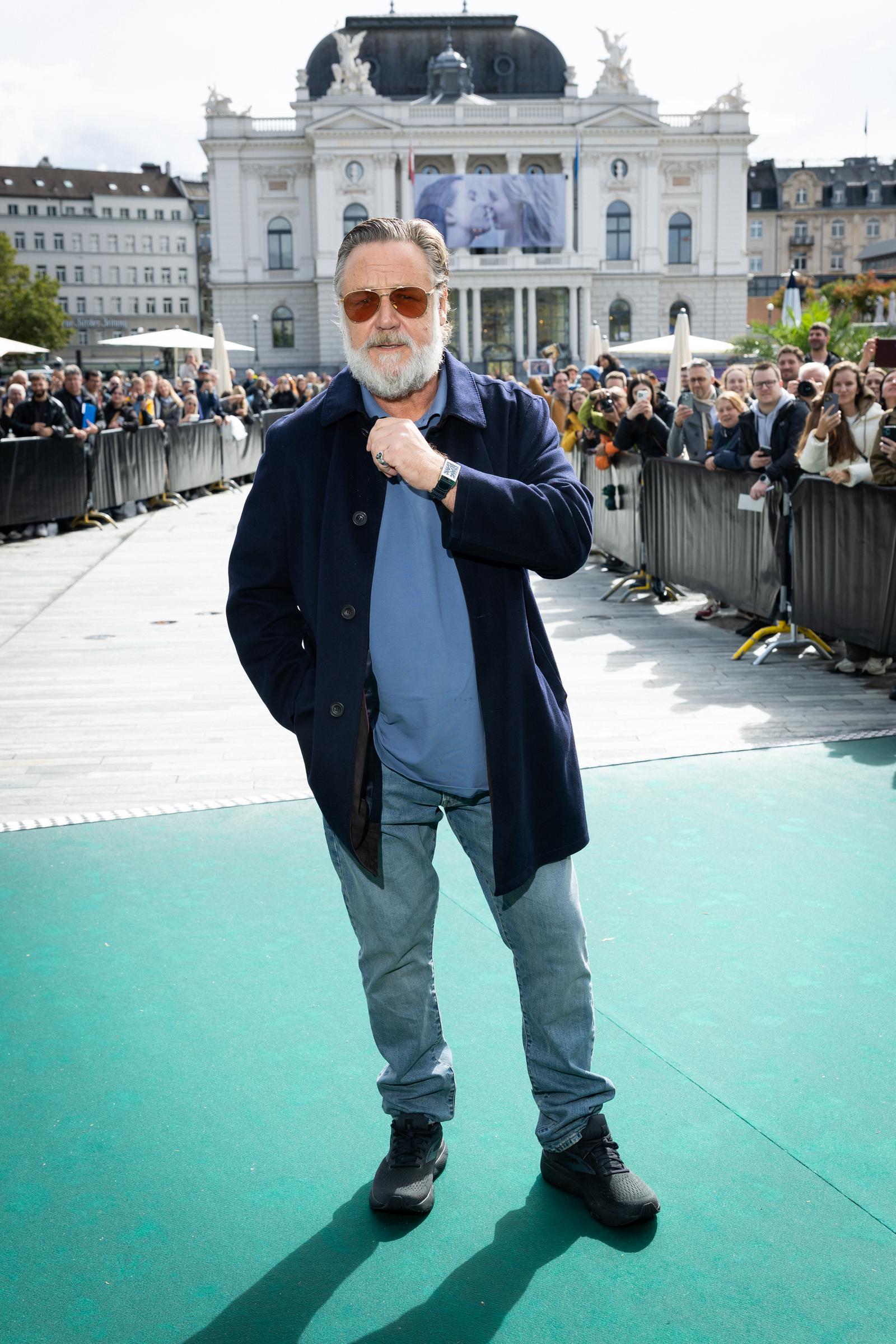 Russell Crowe posed on the green carpet for "Nuremberg" during the 21st Zurich Film Festival on September 27, 2025, in Switzerland. Dressed in a navy coat, blue shirt, and light jeans, he looked noticeably slimmer, revealing the results of his 55-pound weight loss as he greeted fans with a confident stance and trimmed-down frame.