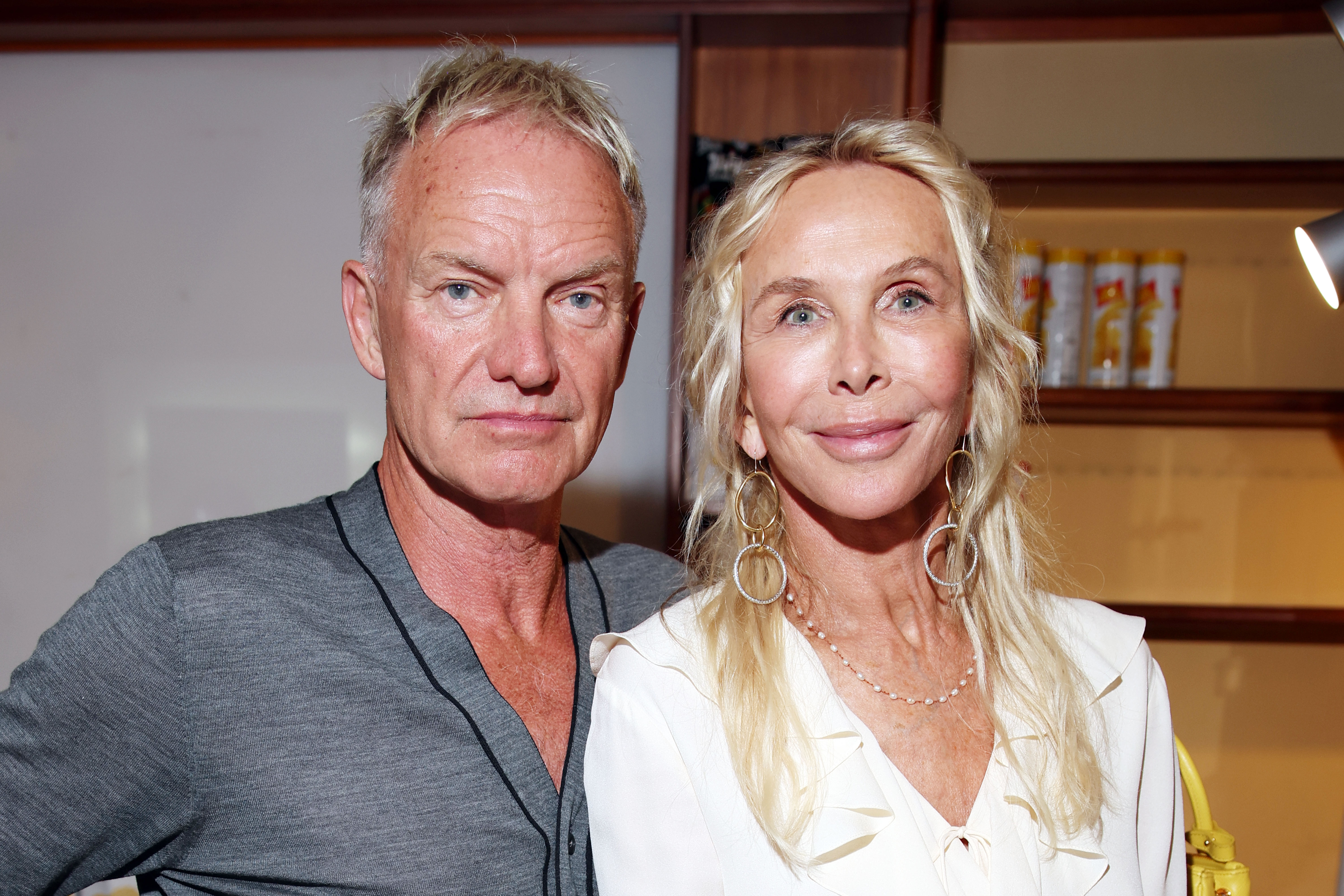 Trudie Styler wears a cream-colored top with a deep v-neckline and ruffled trim, accessorizing with layered necklaces and large, dangling gold hoop earrings, while attending the Ischia Global Festival with Sting on July 7, 2024, in Ischia, Italy.