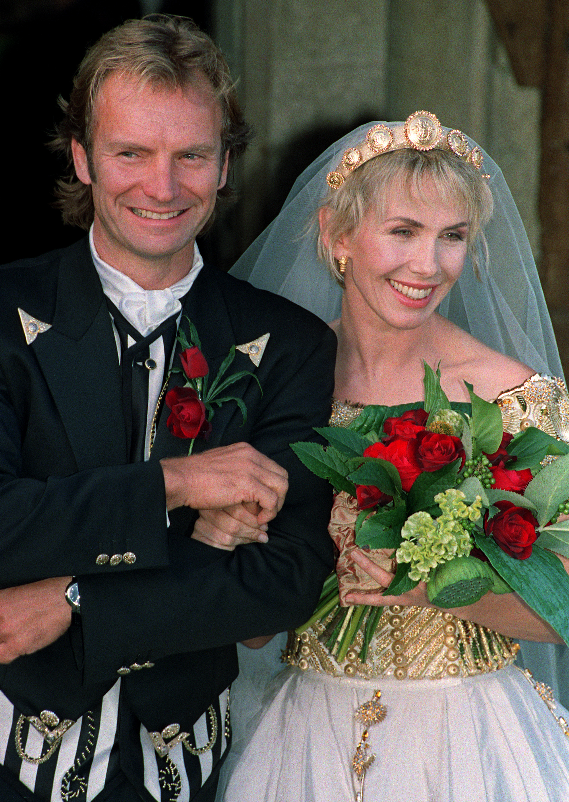 Trudie Styler wears an elaborate off-the-shoulder wedding gown and a gold tiara with a veil over her short blonde hair, as she and Sting attend their church blessing in Great Durnford, Whitshire, on August 22, 1992.