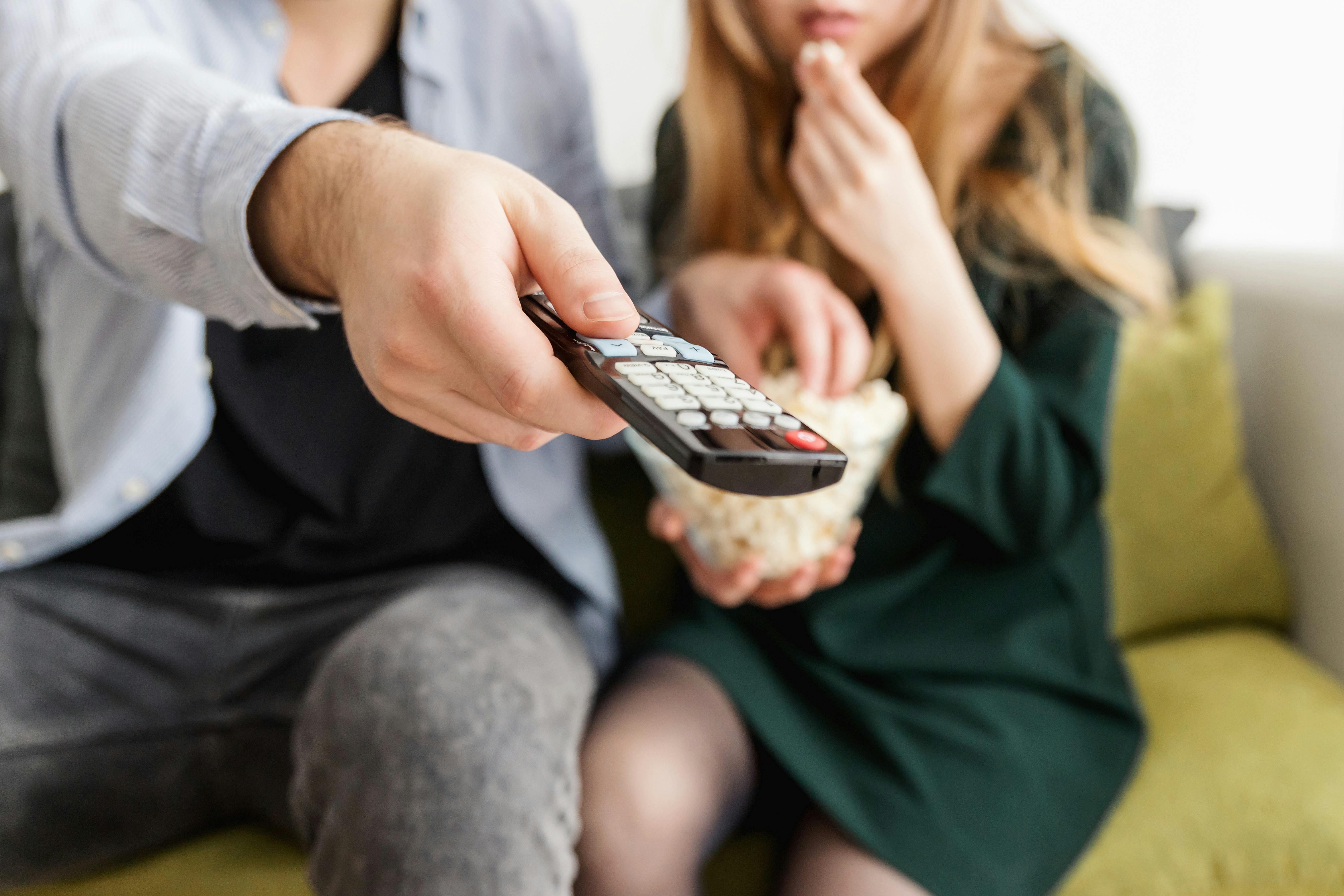 A couple eating popcorn and watching TV | Source: Pexels