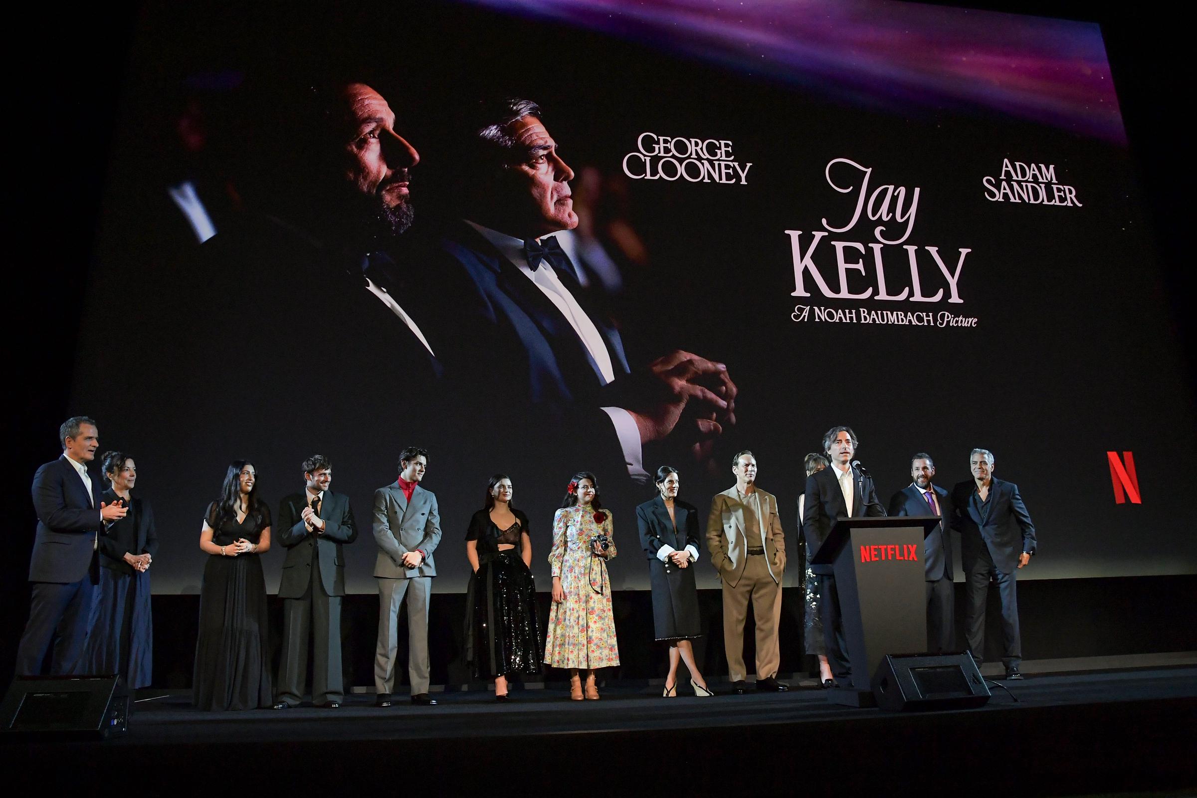 David Heyman, Nina Gold, Sadie Sandler, Charlie Rowe, Louis Partridge, Eve Hewson, Grace Edwards, Riley Keough, Patrick Wilson, Emily Mortimer, Noah Baumbach, Adam Sandler, and George Clooney speak onstage during the premiere of "Jay Kelly."