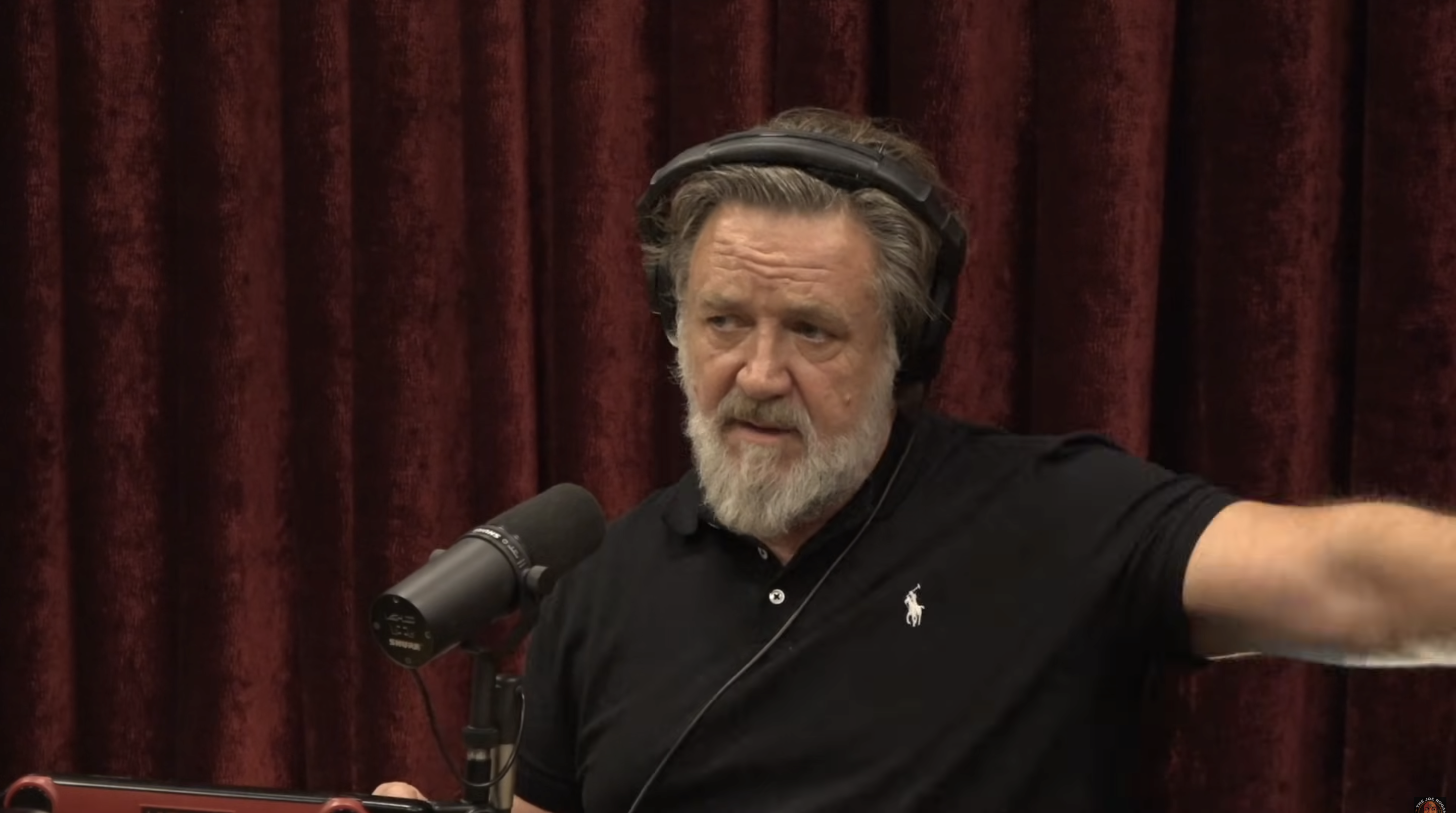 Russell Crowe appeared focused and candid while speaking on "The Joe Rogan Experience" in a video dated November 5, 2025. Dressed in a black polo with headphones on, the actor opened up about his 55-pound weight loss and the health practices that helped him transform. | Source: YouTube/PowerfulJRE