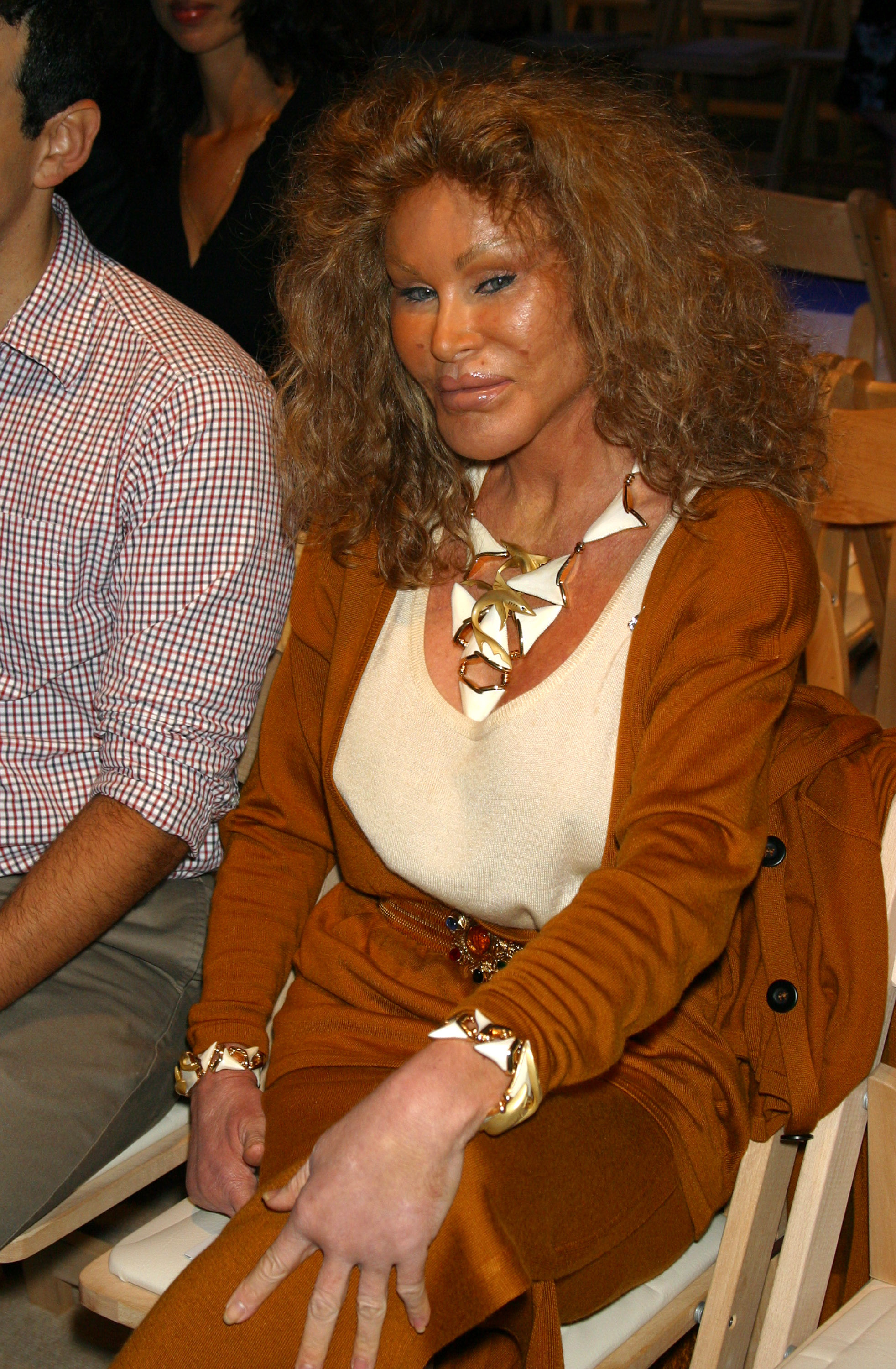 Jocelyne Wildenstein sat with an intense, squinting blue-eyed stare, exaggerated cheekbones, extremely tanned skin, and full, fixed lips holding a slight smile, during the Lloyd Klein show at Mercedes-Benz Fashion Week Spring 2004 on September 12, 2003, in New York, United States.